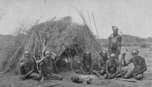 Australian Aborigines posing in front of their wurley.